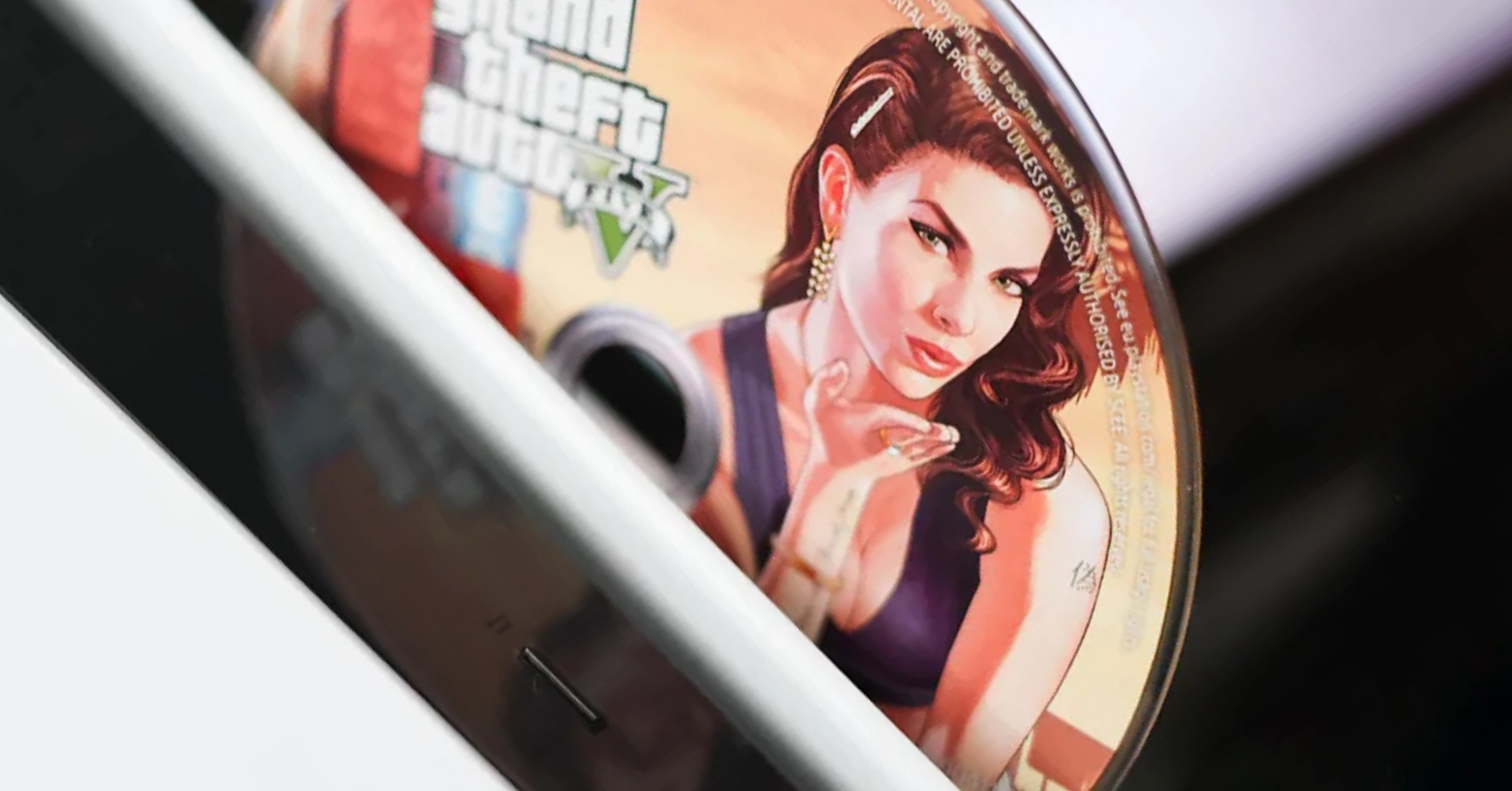 A GTA V game disc being inserted into a console, representing physical game ownership